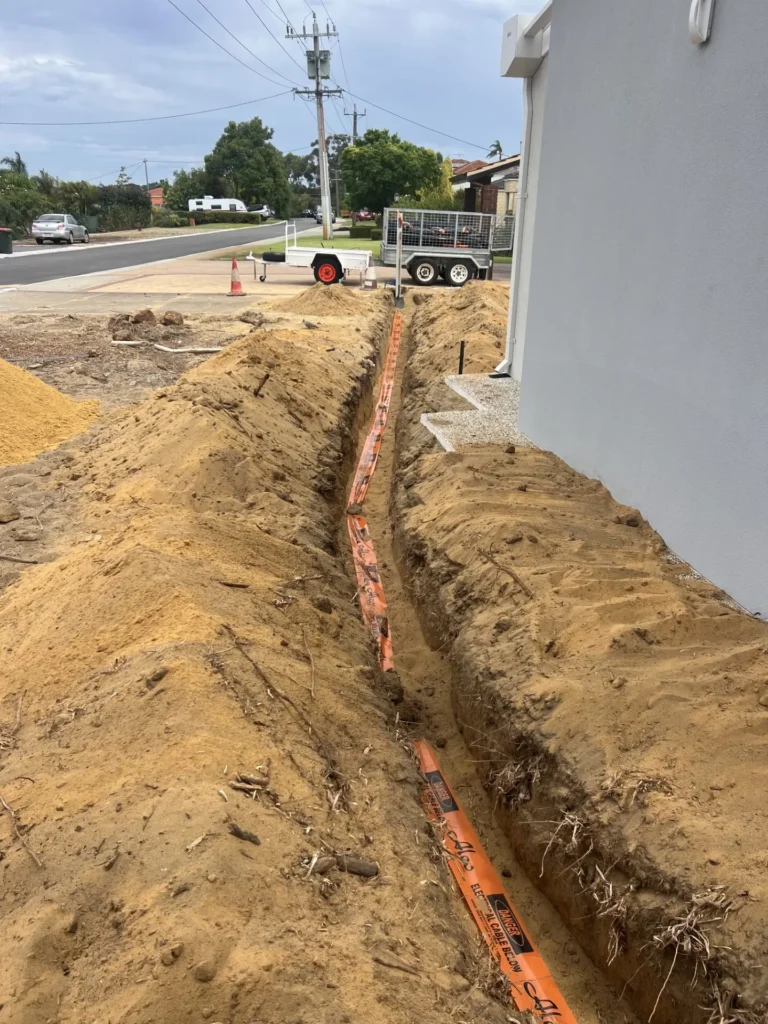 Orange "Danger Electrical Cable Below" marker tape laid the full length of the trench before backfilling