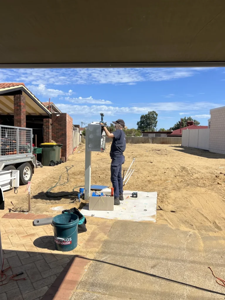 Meg, third-year apprentice electrician at Lifetime Electrics, fitting off the meter enclosure at the new lot's supply position alongside Jay