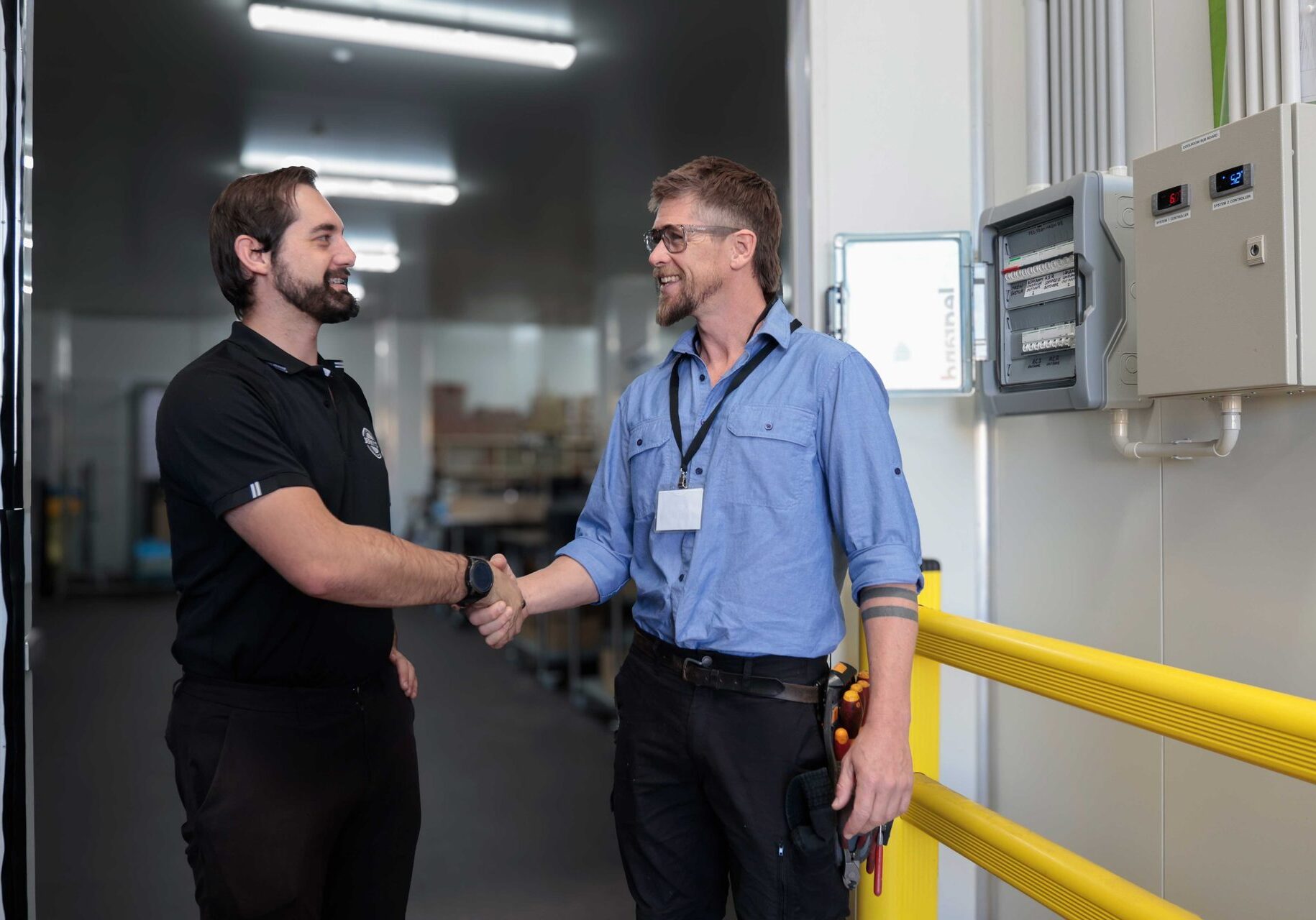 Lifetime Electrics shaking hands with a commercial client in a Perth warehouse